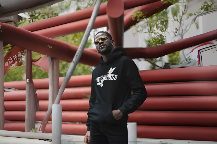 Man wearing a black hoodie with a logo in front of red cylindrical structures